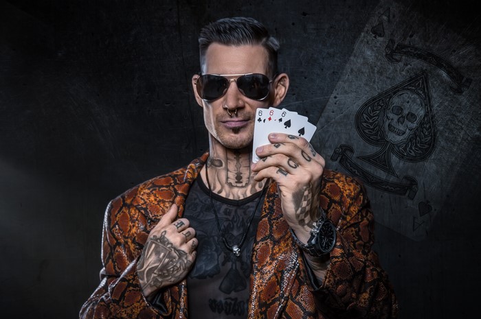 Man with tattoos holding playing cards