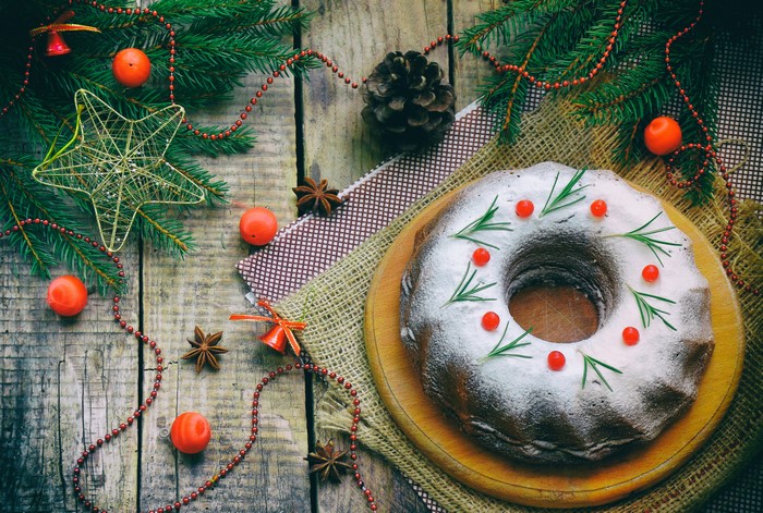 Christmas bundt cake with rosemary and berries on wooden table