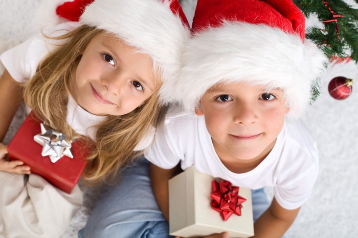 Two children in Santa hats with Christmas gifts
