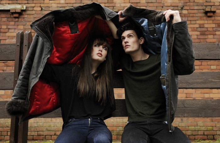 Man and woman sitting under a jacket