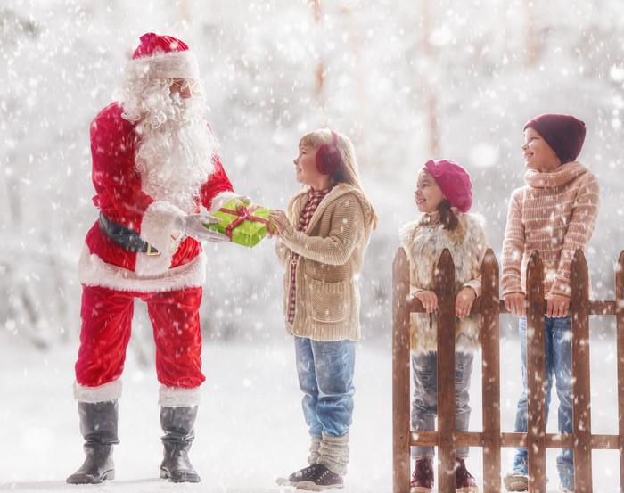 Santa Claus giving gifts to children in snow
