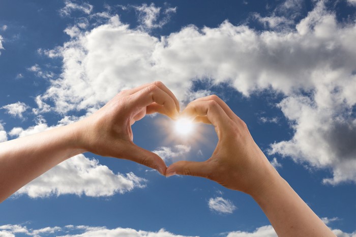 Hands forming a heart shape with the sun