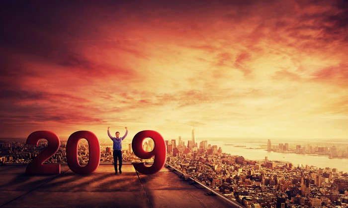 Man celebrating 2019 on a rooftop overlooking a city at sunset