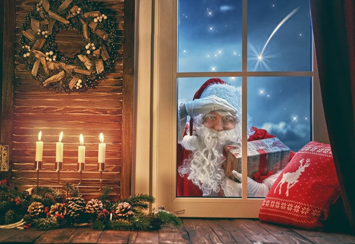 Santa Claus peeking through a window with gifts
