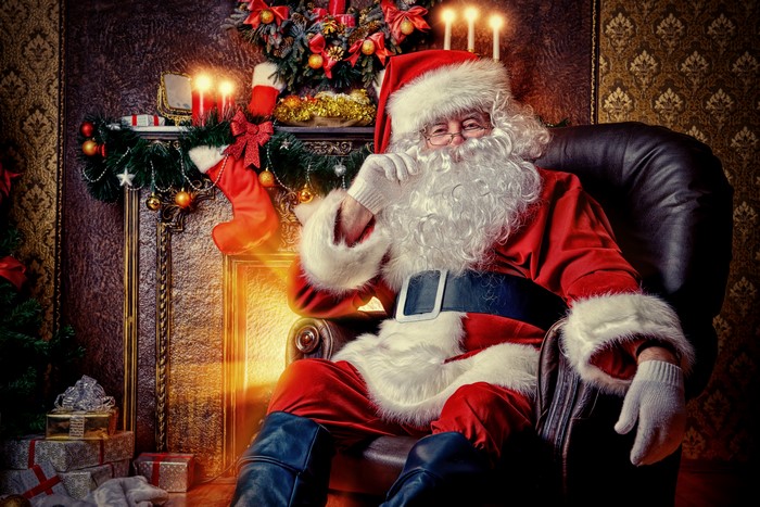 Santa Claus sitting in an armchair by a fireplace