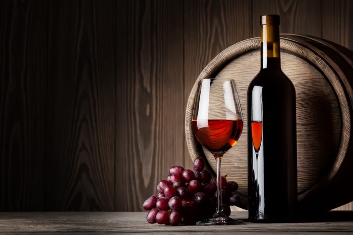 Wine bottle, glass, grapes, and barrel