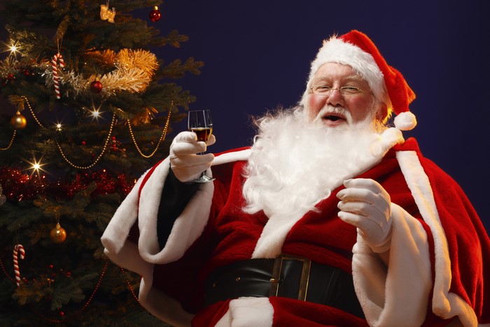 Santa Claus with a drink by a Christmas tree