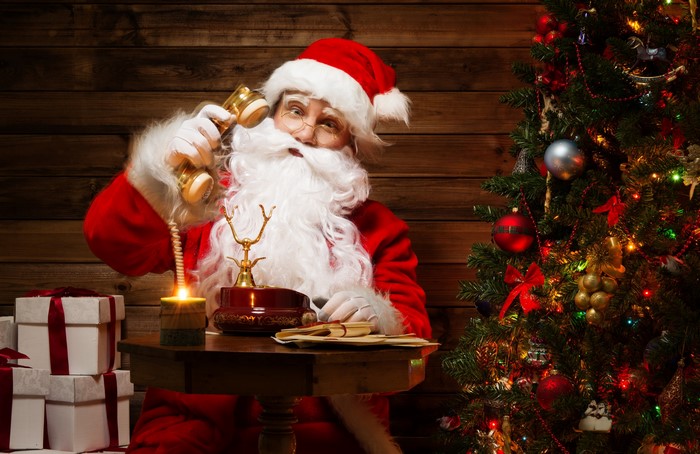 Santa Claus on the phone by Christmas tree