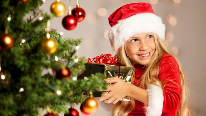 Girl in Santa hat holding a Christmas gift