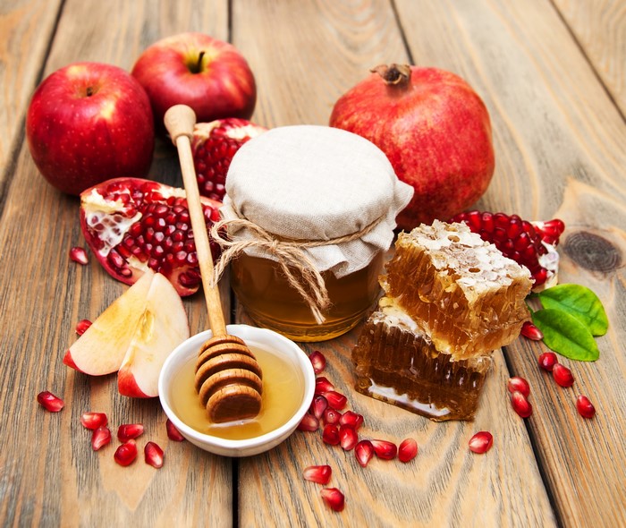 Apples, Pomegranate, Honey, and Honeycomb on Wood