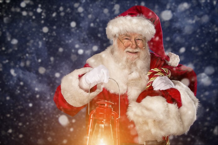 Santa Claus holding a lantern and gift bag
