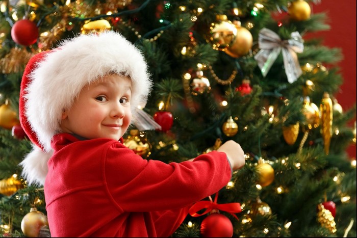Boy in Santa hat decorating Christmas tree