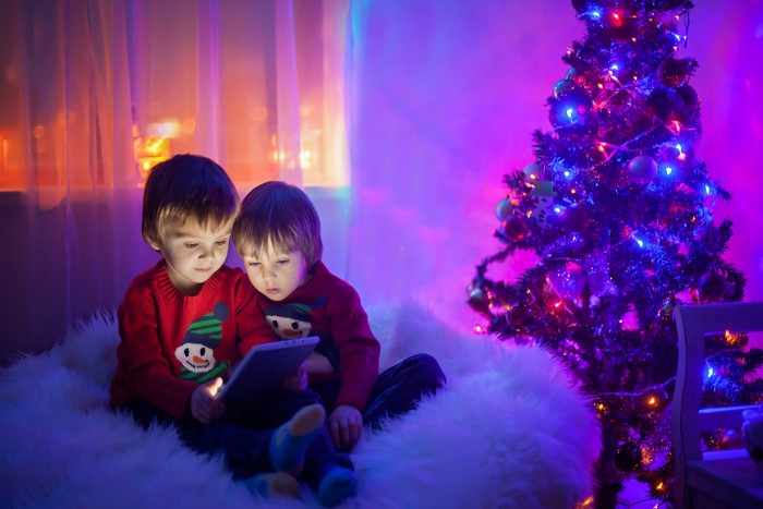 Two Boys Watching Tablet by Christmas Tree