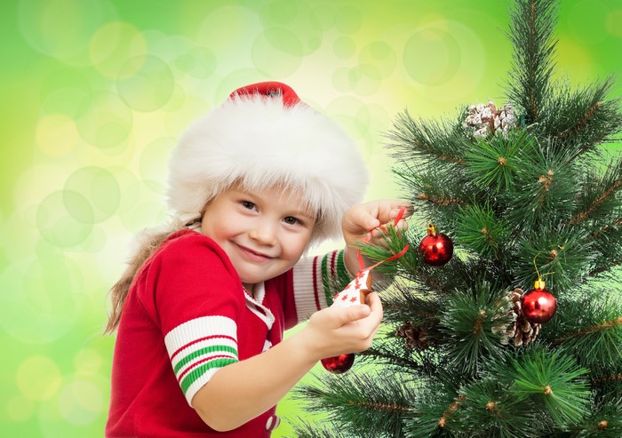 Little girl in Santa hat decorating Christmas tree