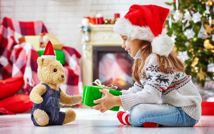 Girl giving a Christmas gift to a teddy bear