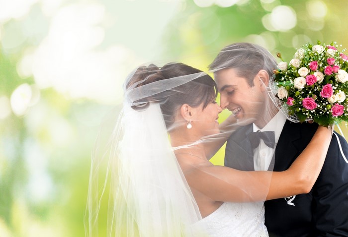 Bride and Groom Embracing Under Veil with Bouquet