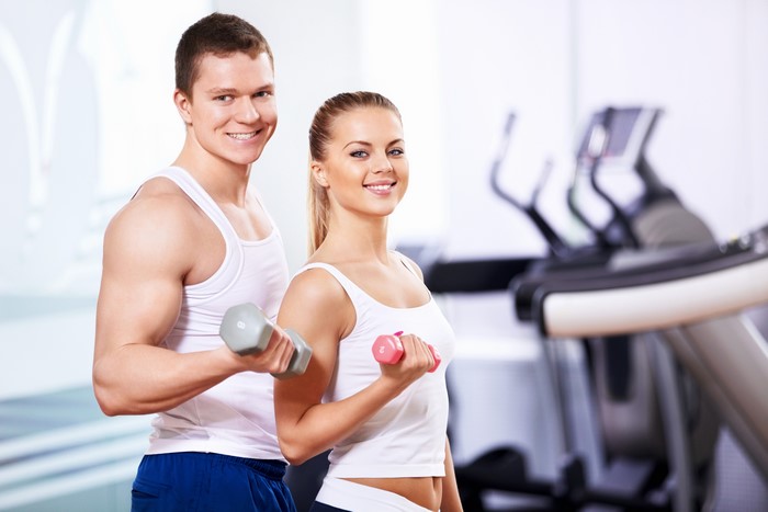 Man and woman exercising with dumbbells in gym
