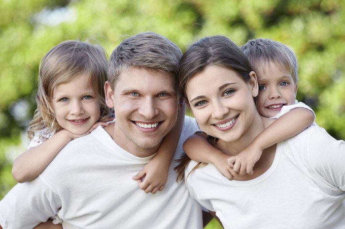 Family with two children smiling outdoors