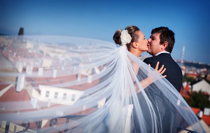 Bride and Groom Kissing with Veil Blowing