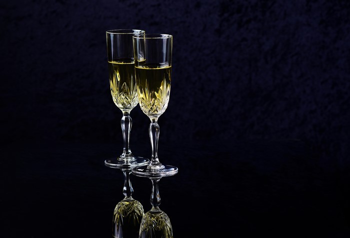 Two champagne glasses with champagne on black background