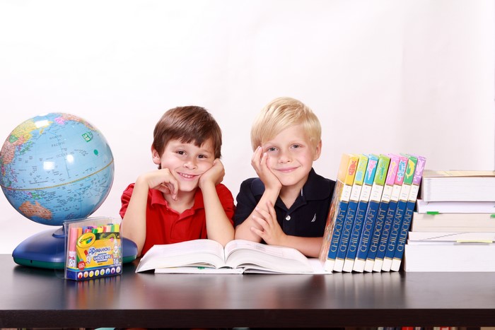 Two boys with school supplies and books