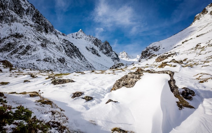 Snowy mountains and rocks under a blue sky