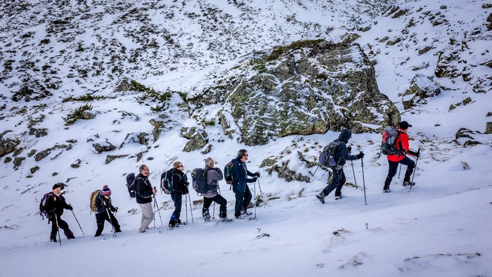 Group of hikers with backpacks walking up a snowy mountain