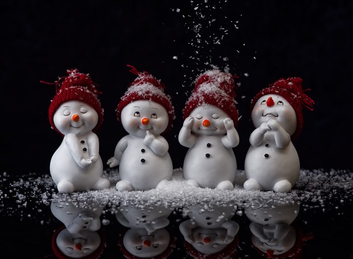 Four snowmen with red hats and snow