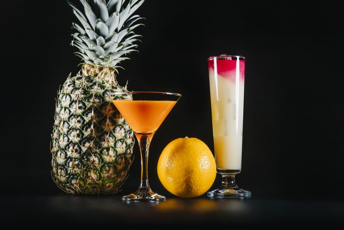 Pineapple, Orange, and Two Cocktails on Black Background