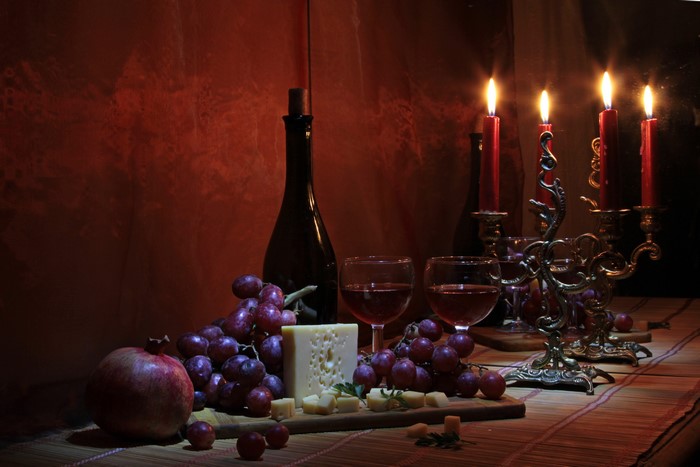 Still-life with wine, grapes, cheese, pomegranate, and candles