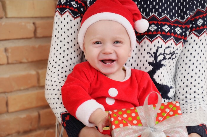 Baby in Santa costume holding a gift