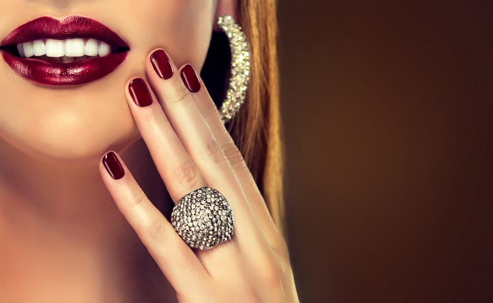 Woman with dark red lips, manicured nails, and diamond ring