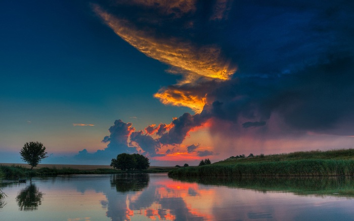 Sunset over a calm lake with dramatic clouds