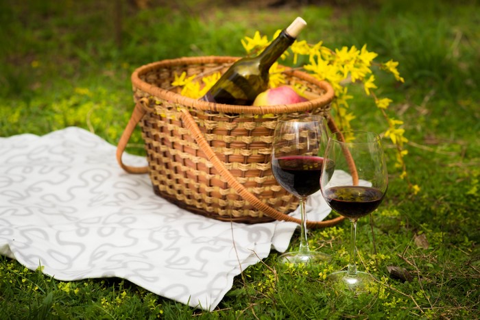 Picnic with Wine and Apple in Wicker Basket on Grass