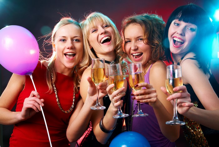 Four women celebrating with champagne and balloons