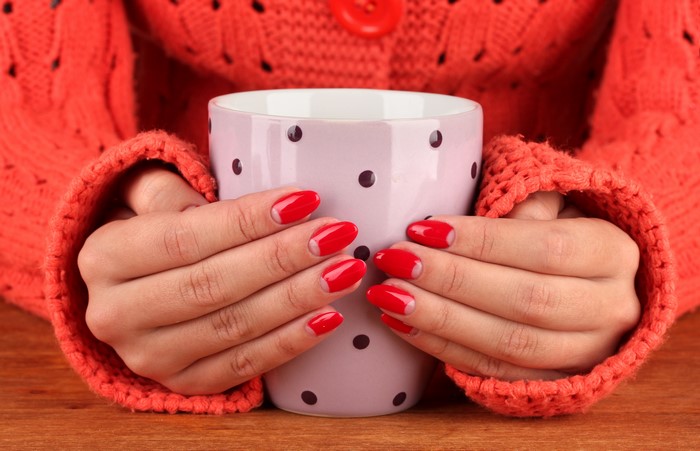 Hands holding a polka dot mug in a sweater