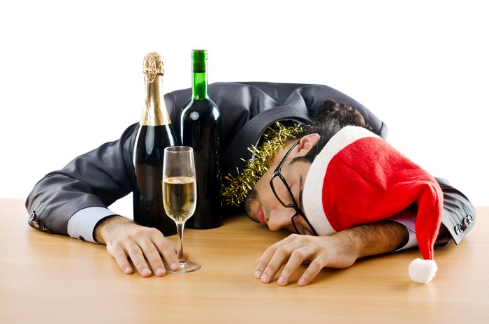Man in Santa hat asleep at desk with wine