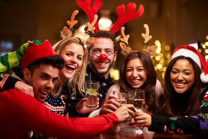 Friends celebrating Christmas with drinks and festive headwear