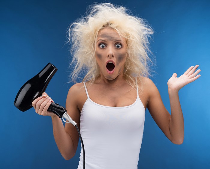 Blonde girl with messy hair holding a hairdryer