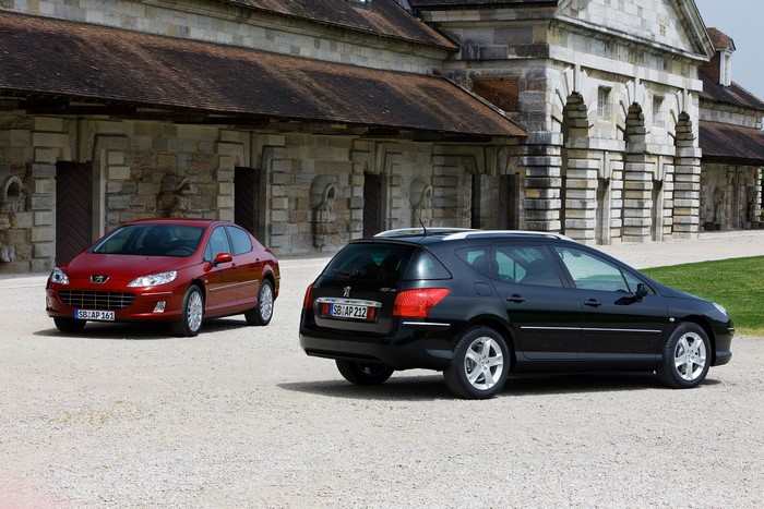 Two Peugeot 407 cars parked outside a building