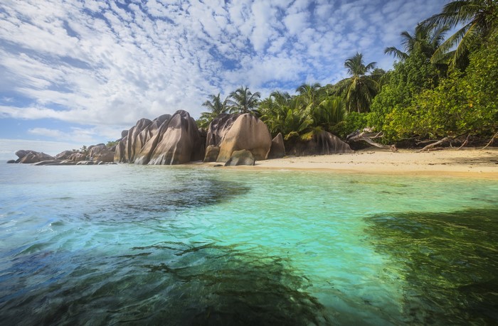 Tropical beach with granite boulders and palm trees