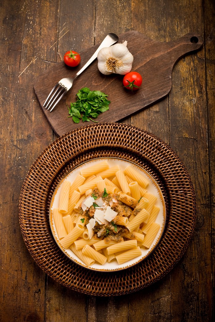 Pasta with tomatoes, garlic, and parsley on a cutting board