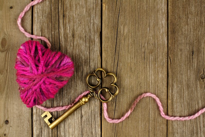 Heart made of yarn with a key on wood