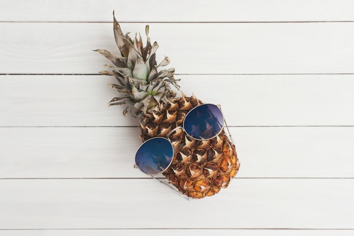 Pineapple wearing sunglasses on wood planks