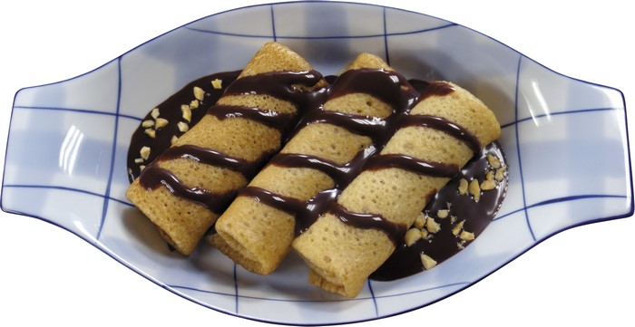 Rolled pancakes with chocolate sauce and nuts on a plate