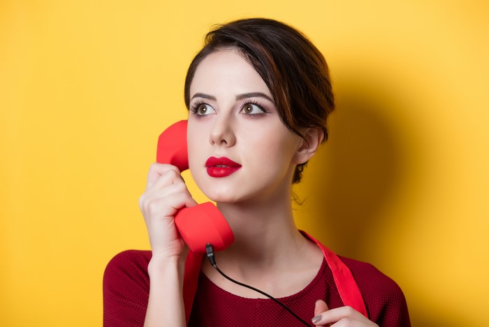 Woman with brown hair holding a red telephone