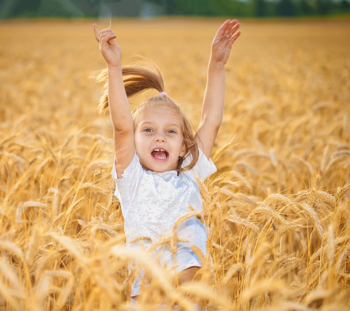 Young girl jumping in a wheat field