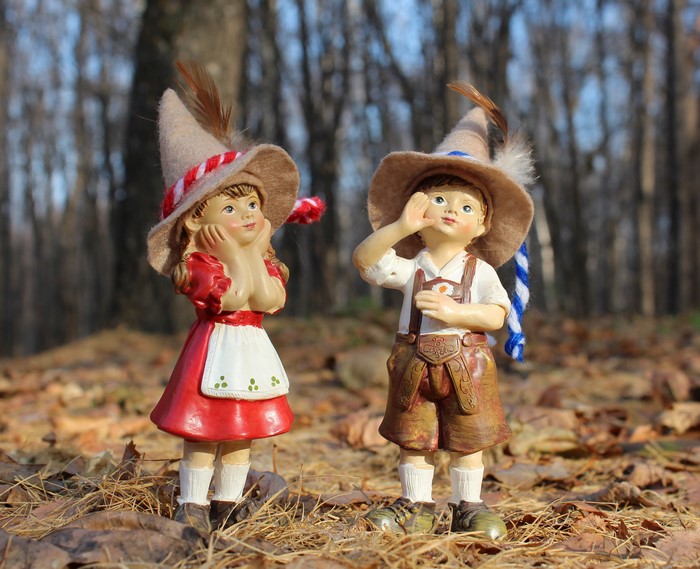 Two figurines of children in traditional German attire in autumn forest