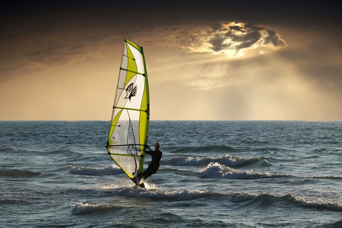 Man windsurfing on the sea at sunset