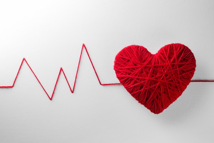 Red yarn heart with electrocardiogram on gray background
